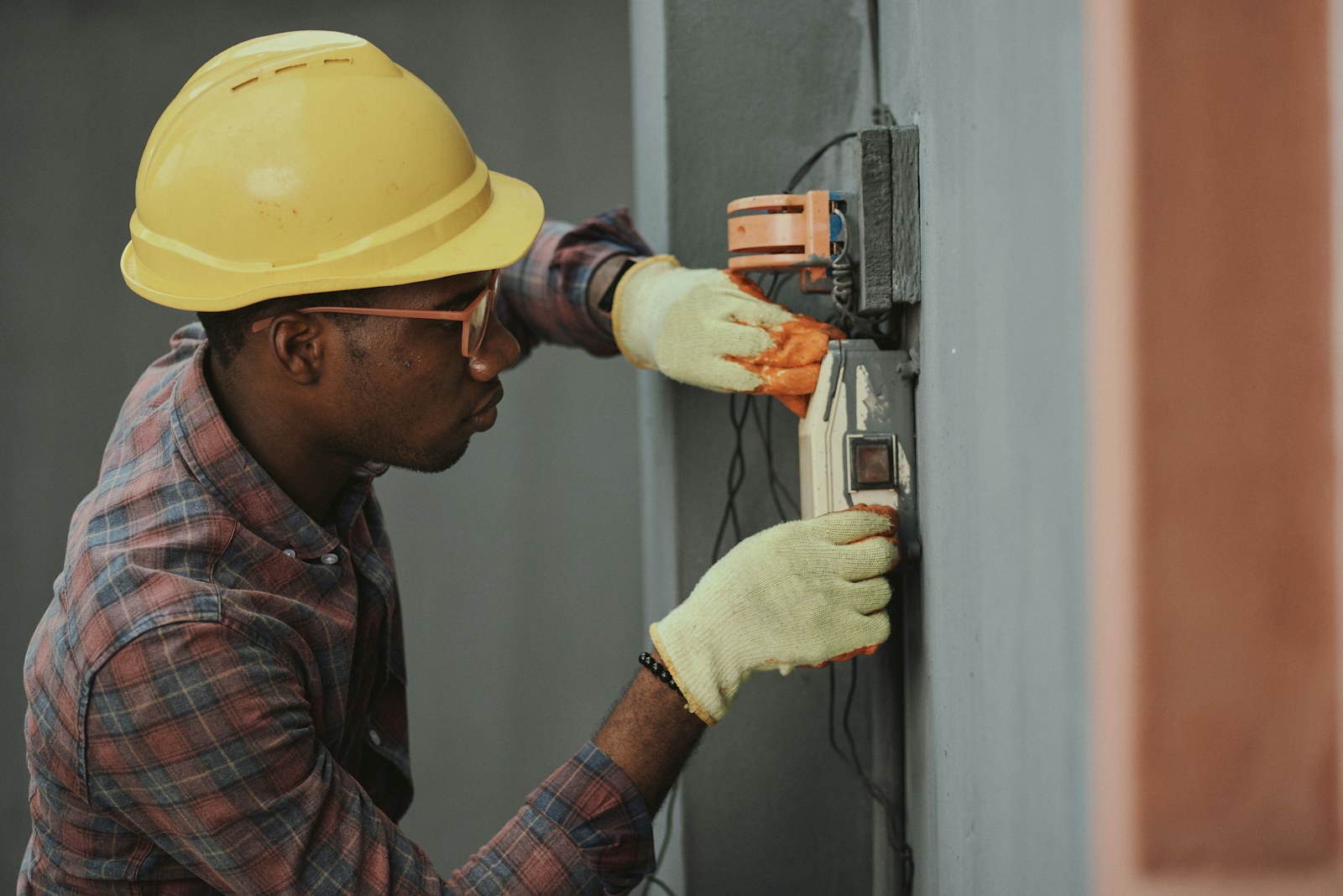 An electrician in safety equipment testing a wall-mounted electrical control