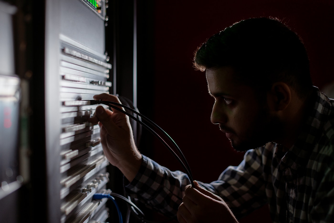 A technician connecting cabling to an industrial controls rack